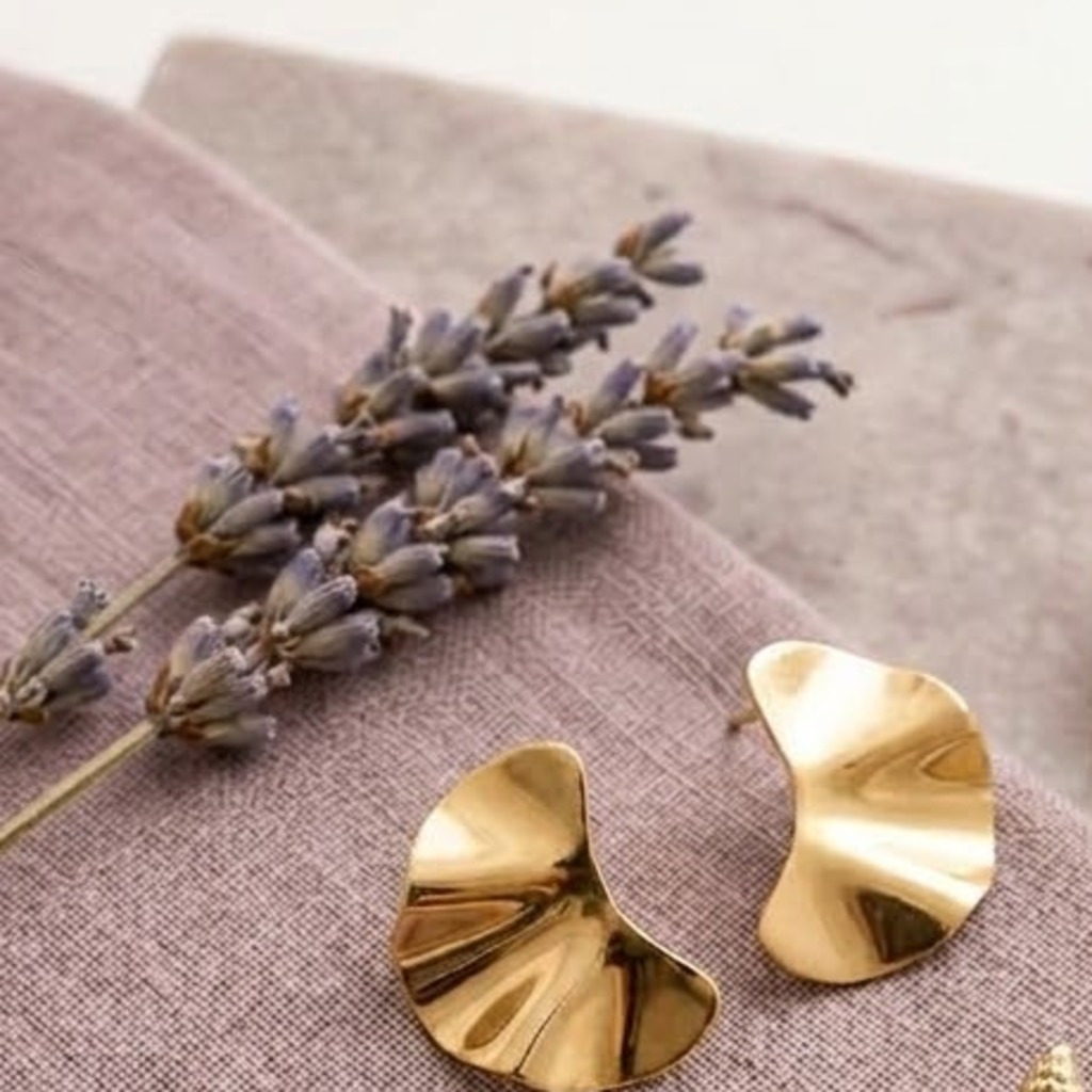 Aros de acero inoxidable en forma de ola sobre tela lavanda